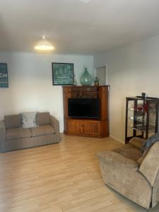 uma sala de estar com um sofá e uma TV de tela plana em Clara Rose Apartment em Waiouru