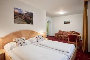 a hotel room with two beds and a couch at Zimmervermietung Zum Weissen Rössl in Sarntal