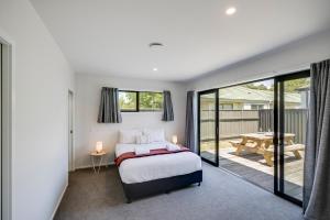 a bedroom with a bed and a balcony at Quiet on Cassin - Taradale in Napier