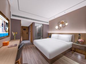 een slaapkamer met een groot wit bed en een bureau bij Orange Chengdu Jinniu Wanda Hotel in Chengdu