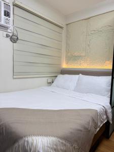 1 dormitorio con 1 cama blanca y microondas en The UrbanNest, en Piapi