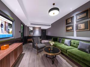 een woonkamer met een groene bank en een tv bij Orange Chengdu Jinniu Wanda Hotel in Chengdu