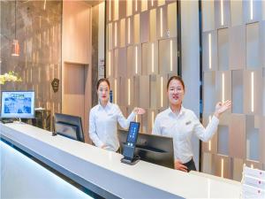 two men standing in an office with their hands up at Echarm Hotel Suzhou Shengze Oriental Extile City in Suzhou