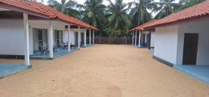 a dirt road between two buildings with palm trees at summer wave in Kalpitiya