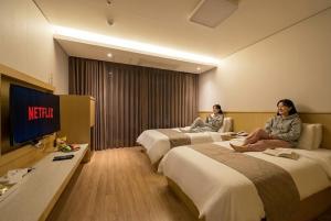 two women sitting on beds in a hotel room at Noble Hotel in Yeosu