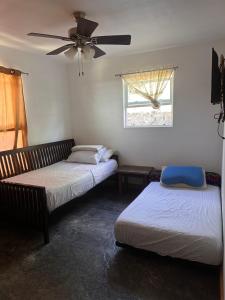 two beds in a room with a ceiling fan at The Gray House 