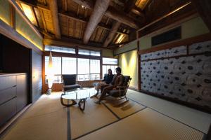 twee personen zitten in stoelen in een woonkamer bij 中尾甚六hotel in Karatsu