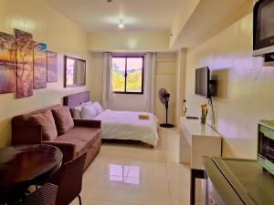 a room with a bed and a couch and a tv at CozyNest Rentals at Brenthill Condominium in Baguio