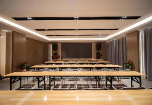 a room with rows of tables and a projection screen at Echarm Hotel Changsha Wuyi Square Xiangya Affiliated 1st Provincial Maternity and Child in Changsha
