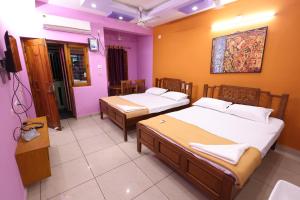 two beds in a room with purple walls at Bluetique Beach House in Kuilapayam