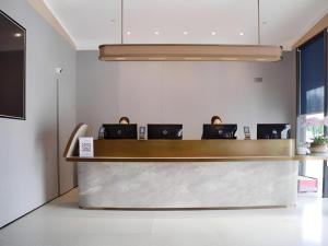 a lobby with a counter with laptops on it at Meijin All Suites Hotel Suzhou in Suzhou