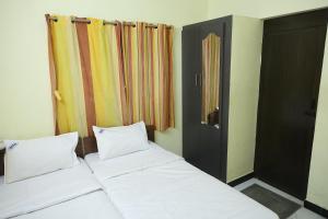 a bedroom with two white beds and a door at Lakshmi Palace Near Madurai Bus Stand in Madurai