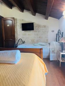 a bedroom with two beds and a tv on the wall at Il Casale di Luisa in Modica