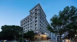 Atour Hotel Urumqi Municipal Government Nanhu People's Square في أورومكي: مبنى أبيض طويل في أحد شوارع المدينة