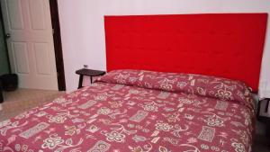łóżko z czerwonym zagłówkiem i różową narzutą w obiekcie Juan Pablo II w mieście San Martín Texmelucan de Labastida