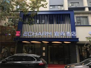 Echarm Hotel Wuhan Plaza Wansongyuan في ووهان: سيارة متوقفة أمام مبنى عليه لافتة