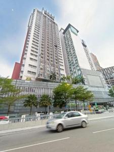 a car driving down a street in front of tall buildings at Taragon Puteri Bintang KLCC View Studio Apartment in Kuala Lumpur