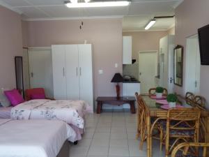 a room with two beds and a table and a desk at Port Elizabeth Apartment in Port Elizabeth