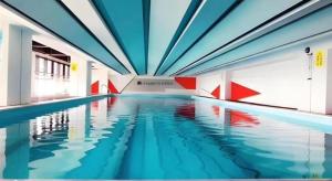 an indoor swimming pool with blue and red ceilings at GreenTree Inn Express Kunming East Passenger Station Huazhicheng in Kunming