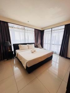a bedroom with a large bed in a room with windows at Taragon Puteri Bintang KLCC View Studio Apartment in Kuala Lumpur