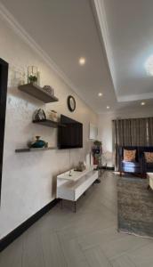 a living room with a couch and a clock on the wall at Beauty Blender Homes - The Executive House in Lilongwe