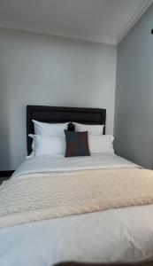 a white bed with a black headboard and white pillows at Beauty Blender Homes - The Executive House in Lilongwe