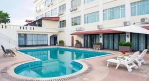 a swimming pool with two chairs and a building at Grand Szechuan Hotel Vientiane in Ban Vat Tay