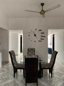 Una mesa de comedor con sillas y un reloj en la pared. en Apartamento familiar Hergom - Grupos de 15 a 30 Pers, en Arboletes