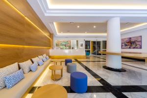a lobby of a hotel with blue chairs and a table at Comitas Floramar in Cala Galdana