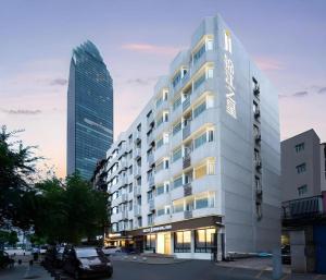 Jinjiang Inn Wuhan Wansongyuan Food Street Qushui Building في ووهان: مبنى طويل وبه سيارة متوقفة أمامه