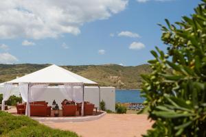 a white tent with chairs under it on a beach at Comitas Tramontana Park in Fornells