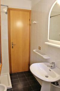 a bathroom with a sink and a wooden door at Appartamenti Rosanna in Grado