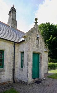 an old stone building with a green door at Magherintemple Lodge in Ballycastle