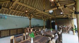 Un comedor con mesas y sillas de madera. en Malioboro Garden Hotel Yogyakarta, en Yogyakarta