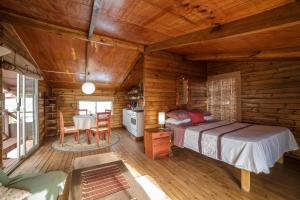 sypialnia w drewnianym domku z łóżkiem i stołem w obiekcie Cabañas Matavai w mieście Hanga Roa