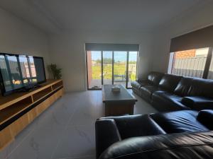 een woonkamer met een zwarte leren bank en een televisie bij Nine in Grovedale