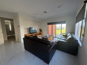 een woonkamer met een bank en een televisie bij Nine in Grovedale