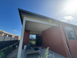 een open deur van een bakstenen huis met een bankje bij Nine in Grovedale