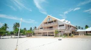 Santa Fe Beach Club في Ocoy: مبنى كبير على شاطئ رملي مع سماء