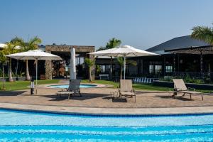 two chairs and umbrellas next to a swimming pool at 356 Ballito Hills in Ballito