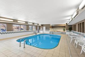a pool in a hotel room with tables and chairs at Quality Inn & Suites Des Moines Airport in Des Moines