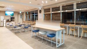 a cafeteria with a row of stools and a table and chairs at Toyoko Inn Tokyo Minowa-eki in Tokyo