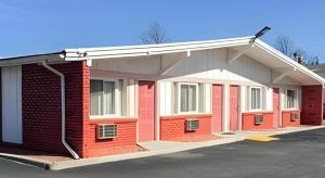 a red and white building in a parking lot at Travelodge by Wyndham Bay Shore Long Island in Bay Shore