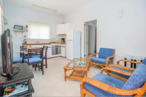 a living room with chairs and a table and a kitchen at Bougainvillea Apartments in Saint Georgeʼs
