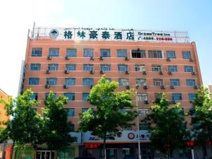 GreenTree Inn Urumqi South Xinhua Road Hotel في أورومكي: مبنى برتقالي كبير أمامه أشجار