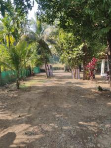 uma estrada de terra com palmeiras num parque em Madhuban Cottage Varsoli- Alibag em Alibag