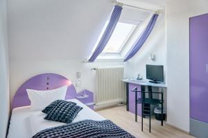- une chambre violette et blanche avec un lit et un bureau dans l'établissement Design-Hotel Zur Abtei, à Aix-la-Chapelle