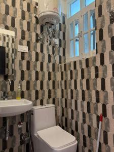 Un baño con inodoro, lavabo y ventana. en Joey's Homestay, en Rishīkesh