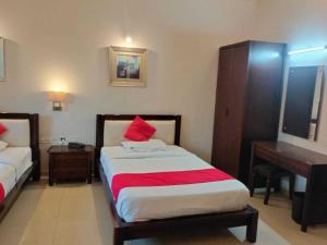una camera da letto con letto con cuscini rossi e scrivania di Hotel O Jaipura Bus Terminal Formerly Navgun a Chattanahalli