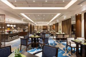 The QUBE Hotel Jingzhou في Caoshi: مطعم مع طاولات وكراسي وبار